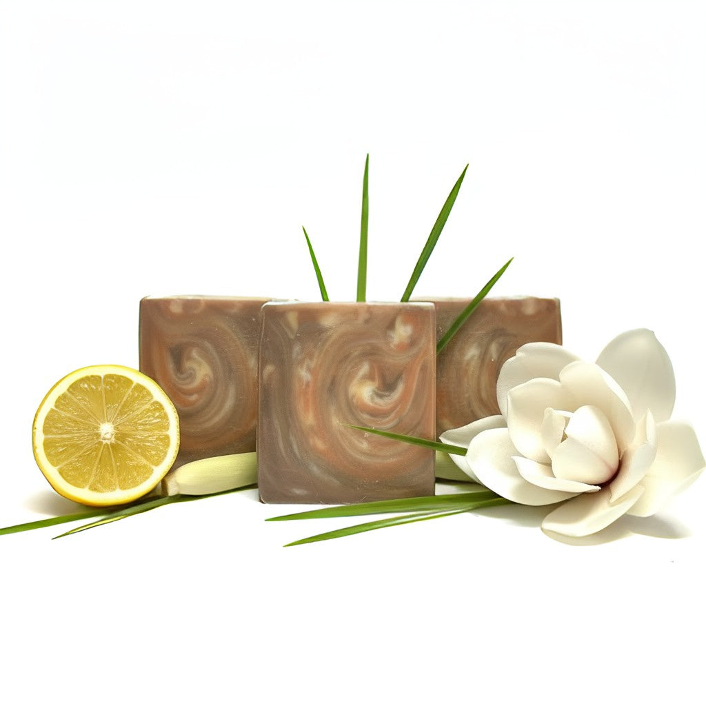 Three swirled brown soaps with a lemon, green leaves, and a white flower on a white background