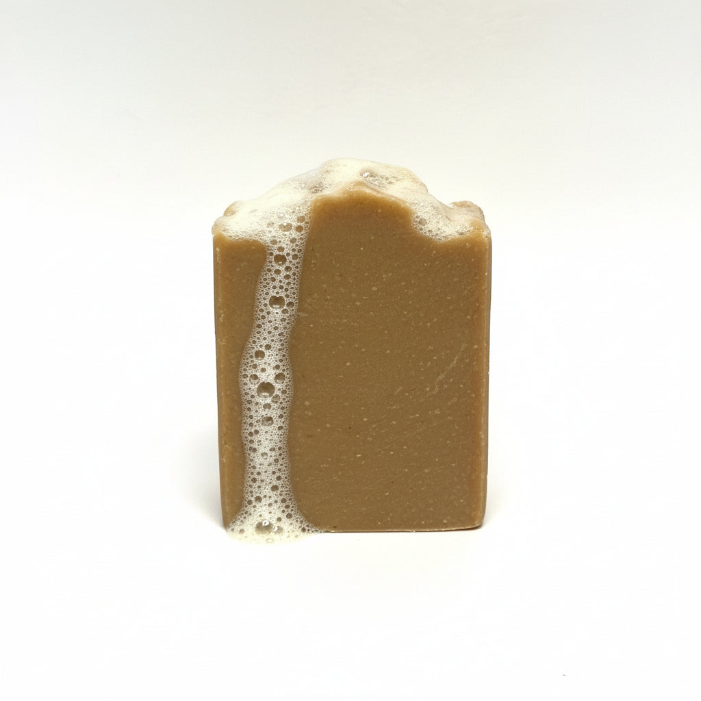 Bar of brown soap with soap suds on a white background
