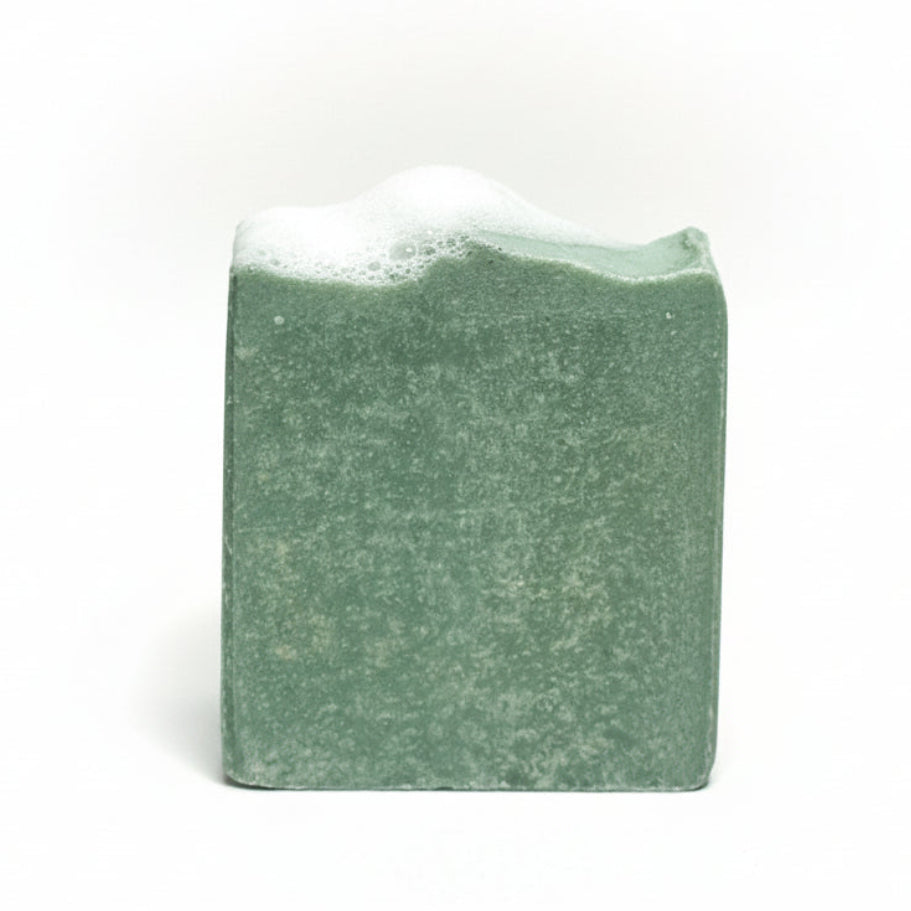 Green bar of soap with a textured surface on a light gray background